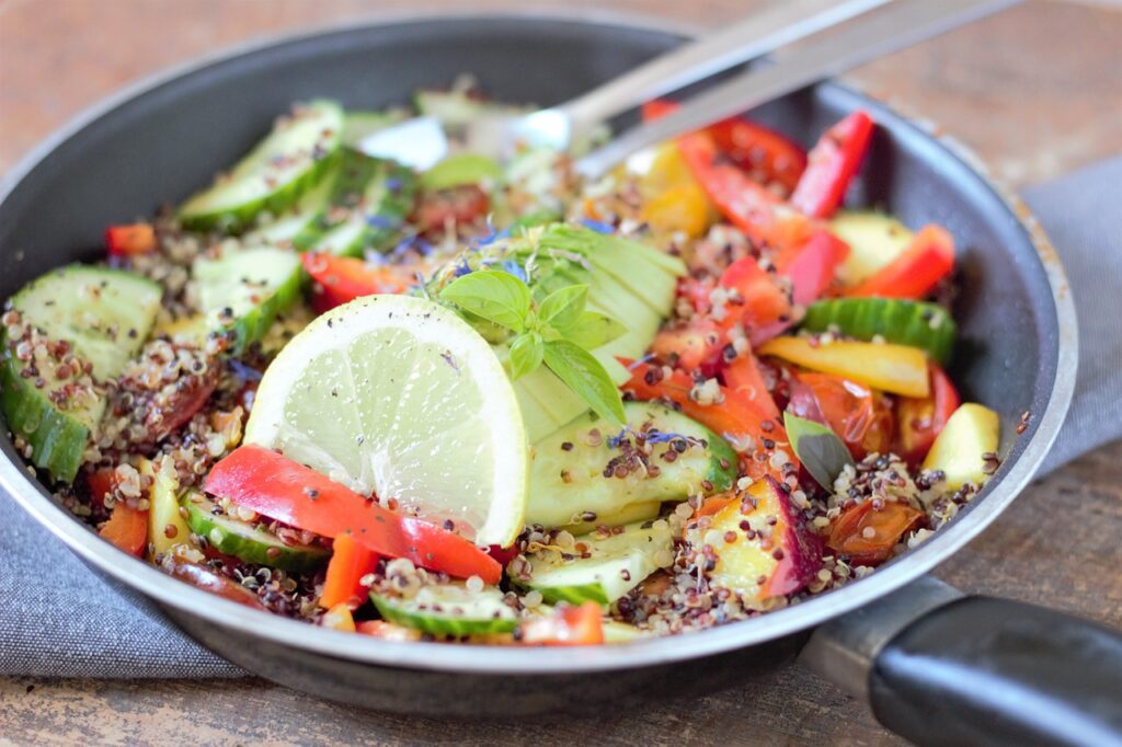 Colorful quinoa veggie bowl with roasted vegetables, avocado, and pumpkin seeds.