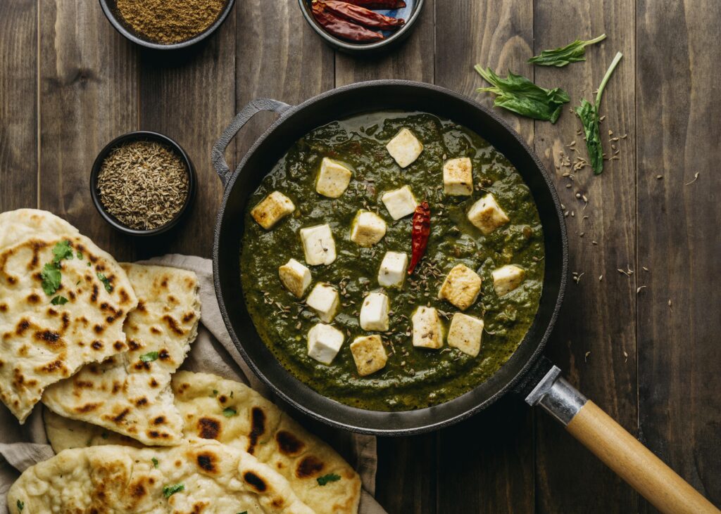 Spinach curry with paneer cubes served with naan.